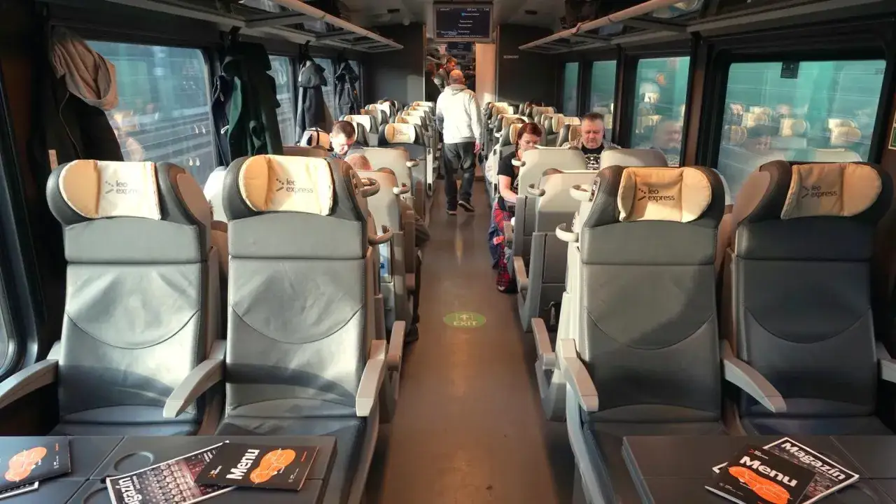 Wnętrze pociągu Leo Express, którym podróżujesz z Krakowa do Pragi. Wygodne siedzenia i stoliki z menu czekają na pasażerów.