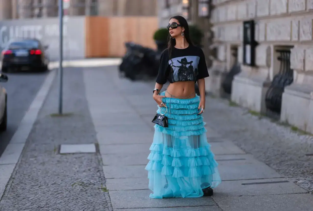 Krótki czarny t-shirt z grafiką i błękitna tiulowa spódnica z falbanami – idealne połączenie, by zadać pytanie: jaka bluzka do tiulowej spódnicy?