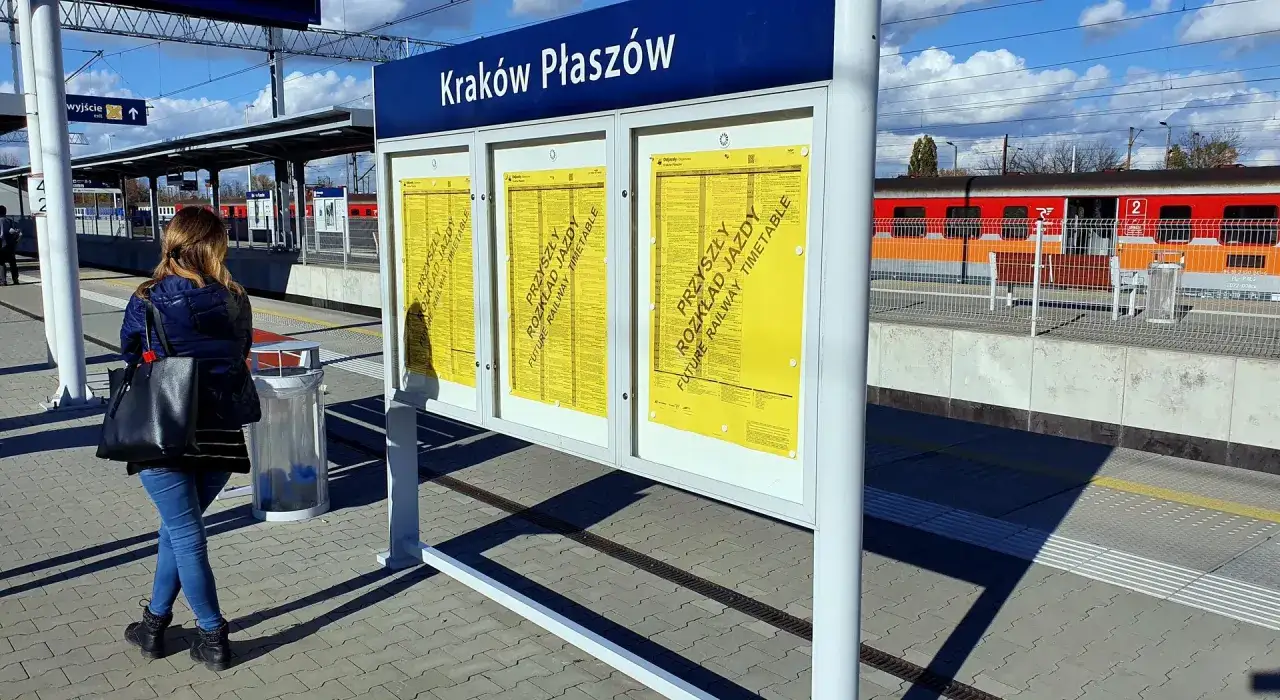 Kobieta sprawdza tablicę z informacją o zmianie rozkładu jazdy PKP na stacji Kraków Płaszów.
