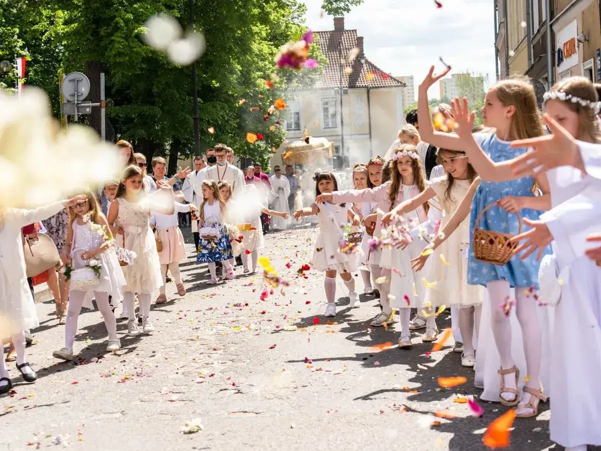 15 czerwca. Dzieci w białych strojach sypią kwiaty podczas procesji.