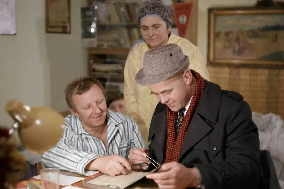 Trzech ludzi przy stole, jeden w kapeluszu przegląda album, być może z myślą o najpopularniejszych polskich filmach.