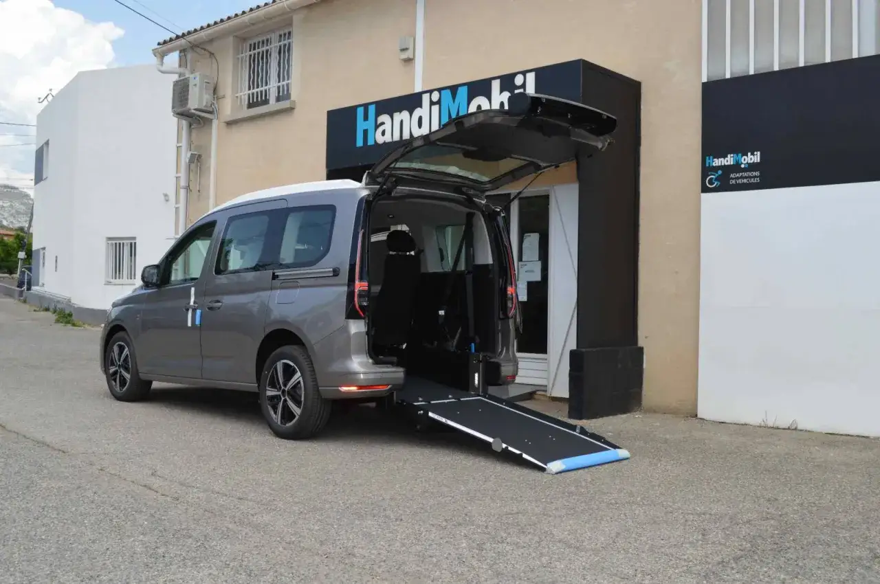 Un fourgon am&eacute;nag&eacute; PMR avec rampe d'acc&egrave;s d&eacute;ploy&eacute;e, pr&ecirc;t &agrave; faciliter le transport.