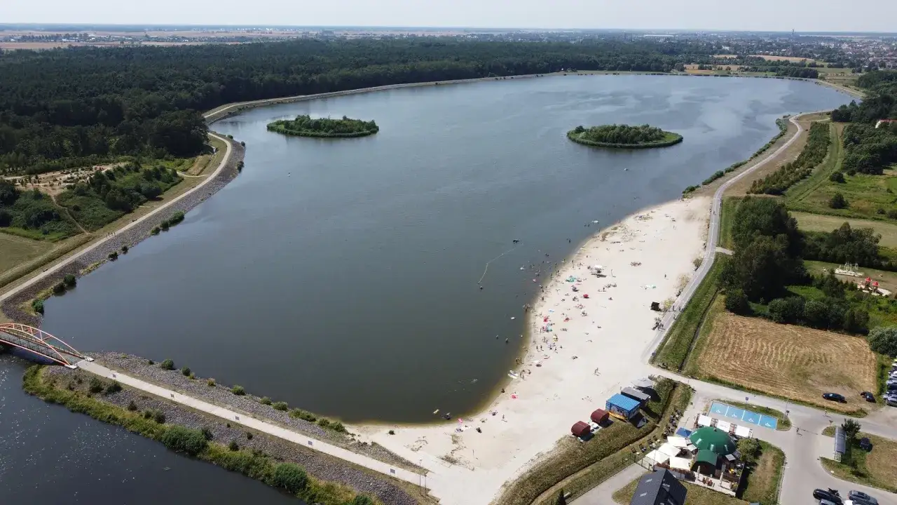 Odkryj magiczne miejsca opolskie: piaszczysta plaża nad jeziorem, wyspy pośr&oacute;d wody i zielone tereny rekreacyjne.