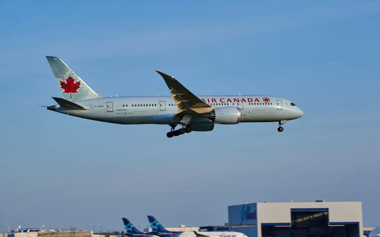 Samolot Air Canada z liściem klonu na ogonie zbliża się do lądowania. Zastanawiasz się, ile trwa lot do Kanady z Polski?
