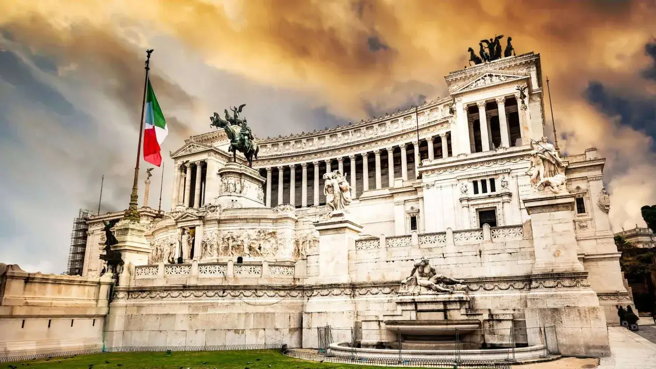 Le monument &agrave; Victor-Emmanuel II &agrave; Rome, avec son drapeau italien flottant sous un ciel orageux.