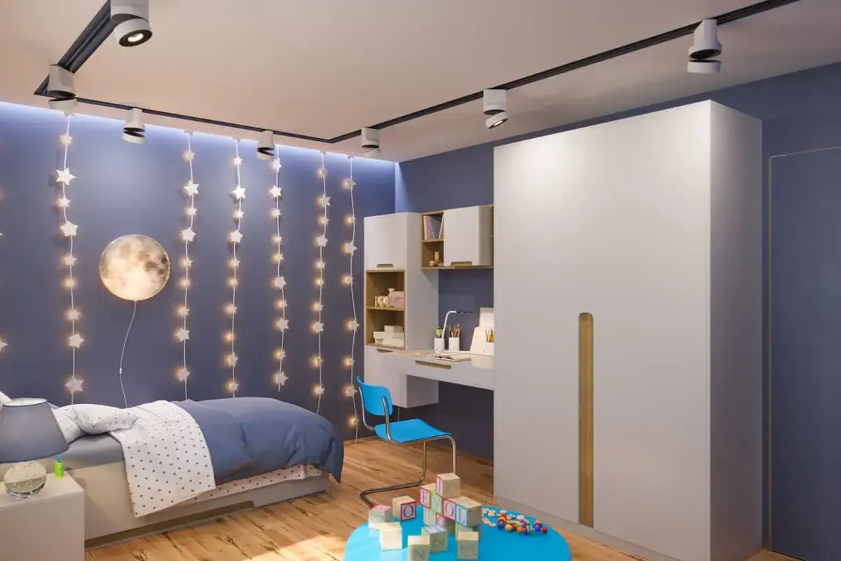 Habitaci&oacute;n juvenil con pared azul y guirnaldas de estrellas. Un ejemplo perfecto de c&oacute;mo pintar habitaci&oacute;n juvenil dos colores, combinando el azul con blanco y madera.