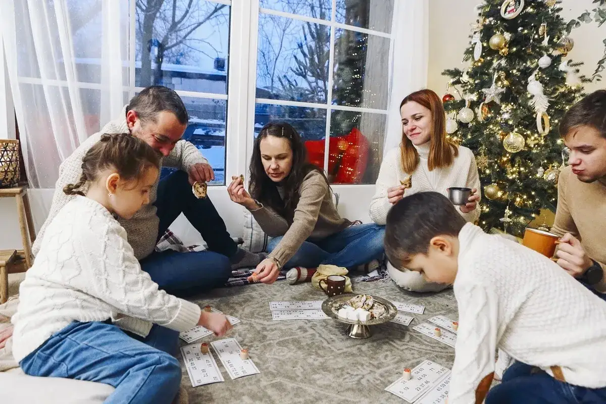 Familia reunida jugando juegos interactivos de navidad junto al &aacute;rbol.