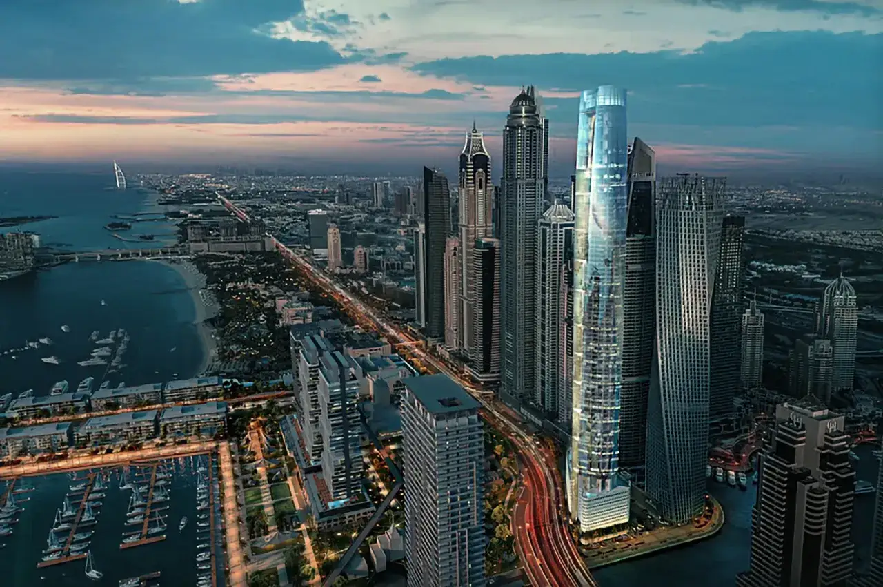 Wieżowce Dubaju o zmierzchu, z widokiem na marinę i plażę. Wśród nich lśni najwyższy hotel na świecie, otoczony innymi drapaczami chmur.