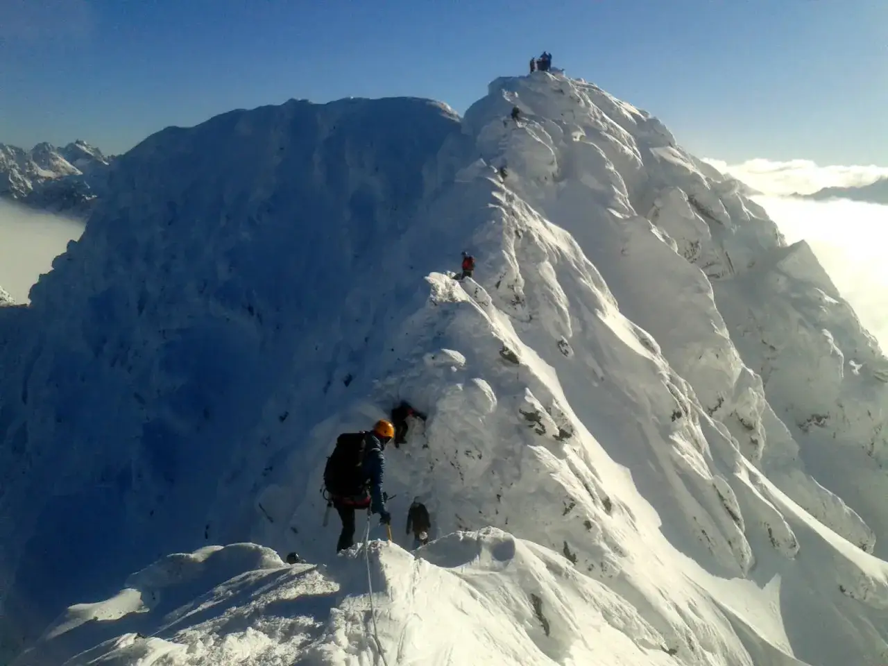 Alpinisci pokonują śnieżny grzbiet. Świnicka przełęcz trudność jest widoczna w stromych zboczach i wymagającej trasie.
