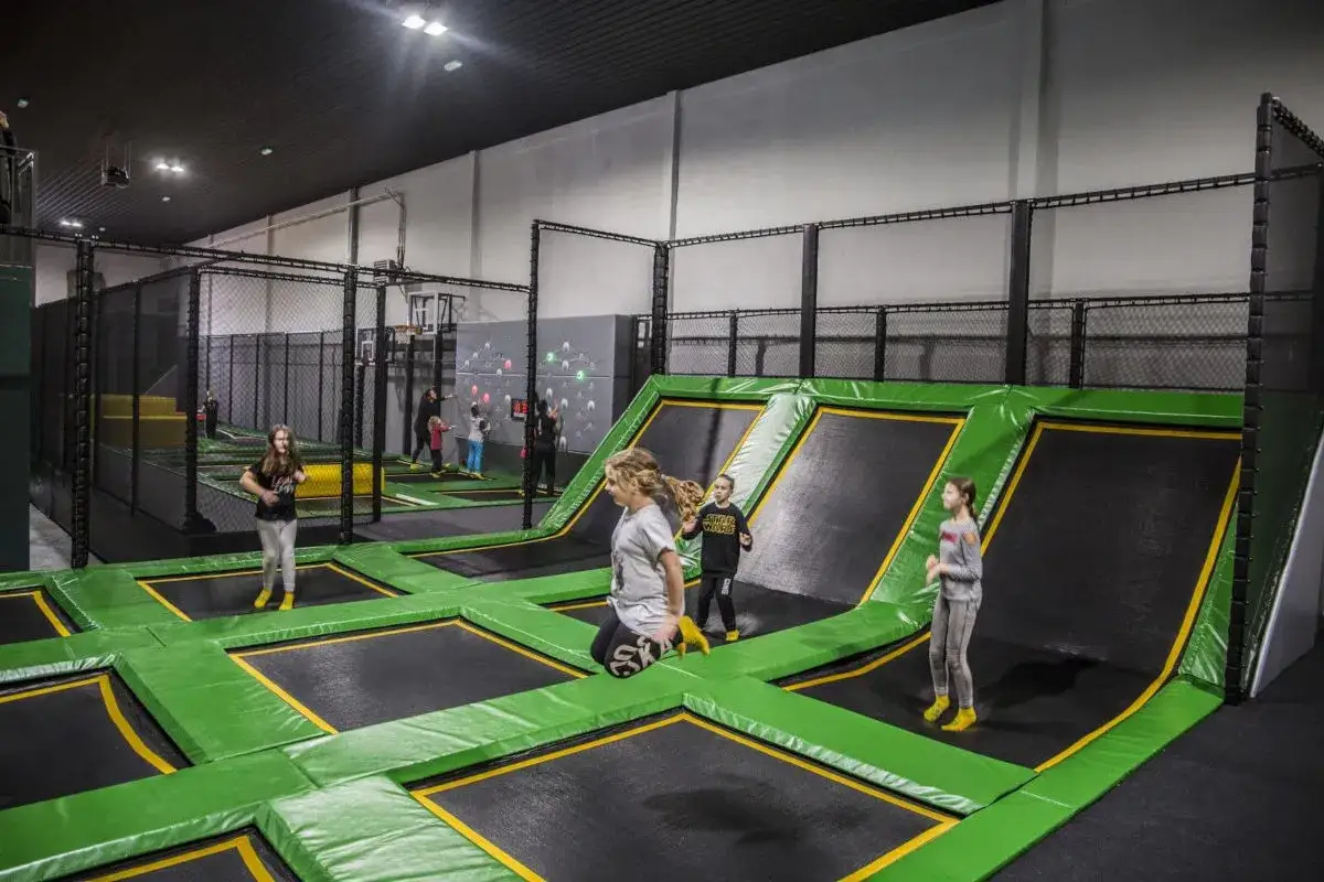 Dzieci skaczą na trampolinach w parku rozrywki. To świetne miejsce, gdzie znajdziesz wiele atrakcji dla dzieci w Jeleniej Górze.