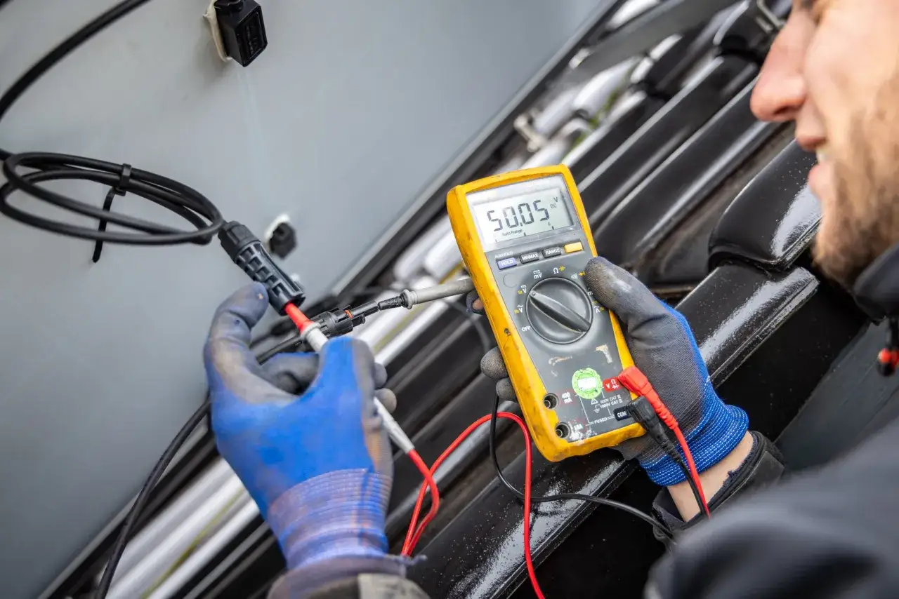 Ein Techniker misst mit einem Multimeter die Spannung an einem Solarmodul. Das Ger&auml;t zeigt 50,05 V an.