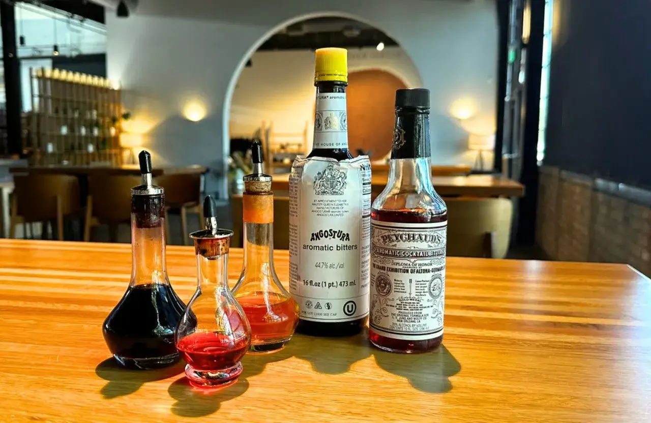 Kolekcja buteleczek z aromatycznymi bitterami, w tym Angostura i Peychaud's, gotowa do dodania głębi i **bitter** smaku do koktajli.