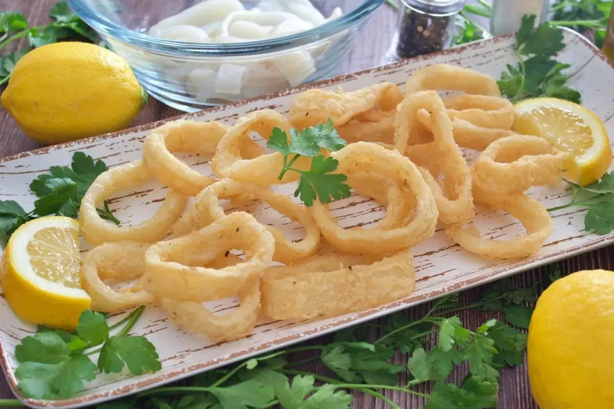 Calamares a la andaluza dorados y crujientes, servidos con limones frescos y perejil.