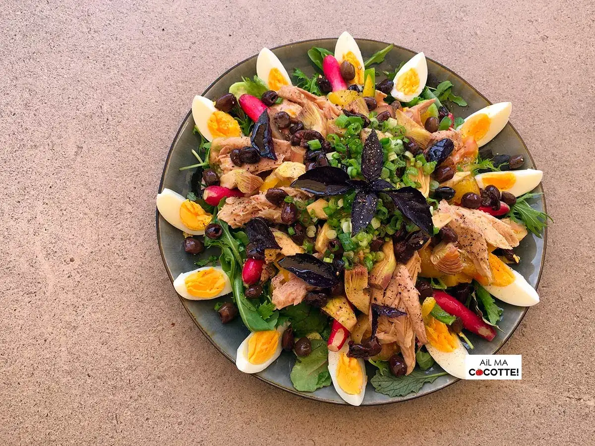 Salade ni&ccedil;oise avec riz, &oelig;ufs durs, thon, olives, artichauts et radis, garnie d'herbes fra&icirc;ches. Un d&eacute;lice color&eacute; !