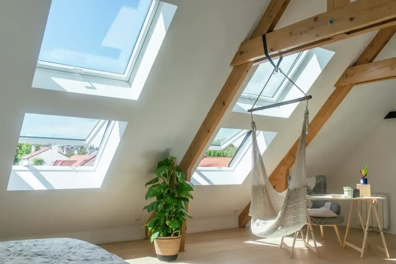 Interno mansarda con montaggio lucernario, amaca sospesa e scrivania. Luce naturale inonda lo spazio.