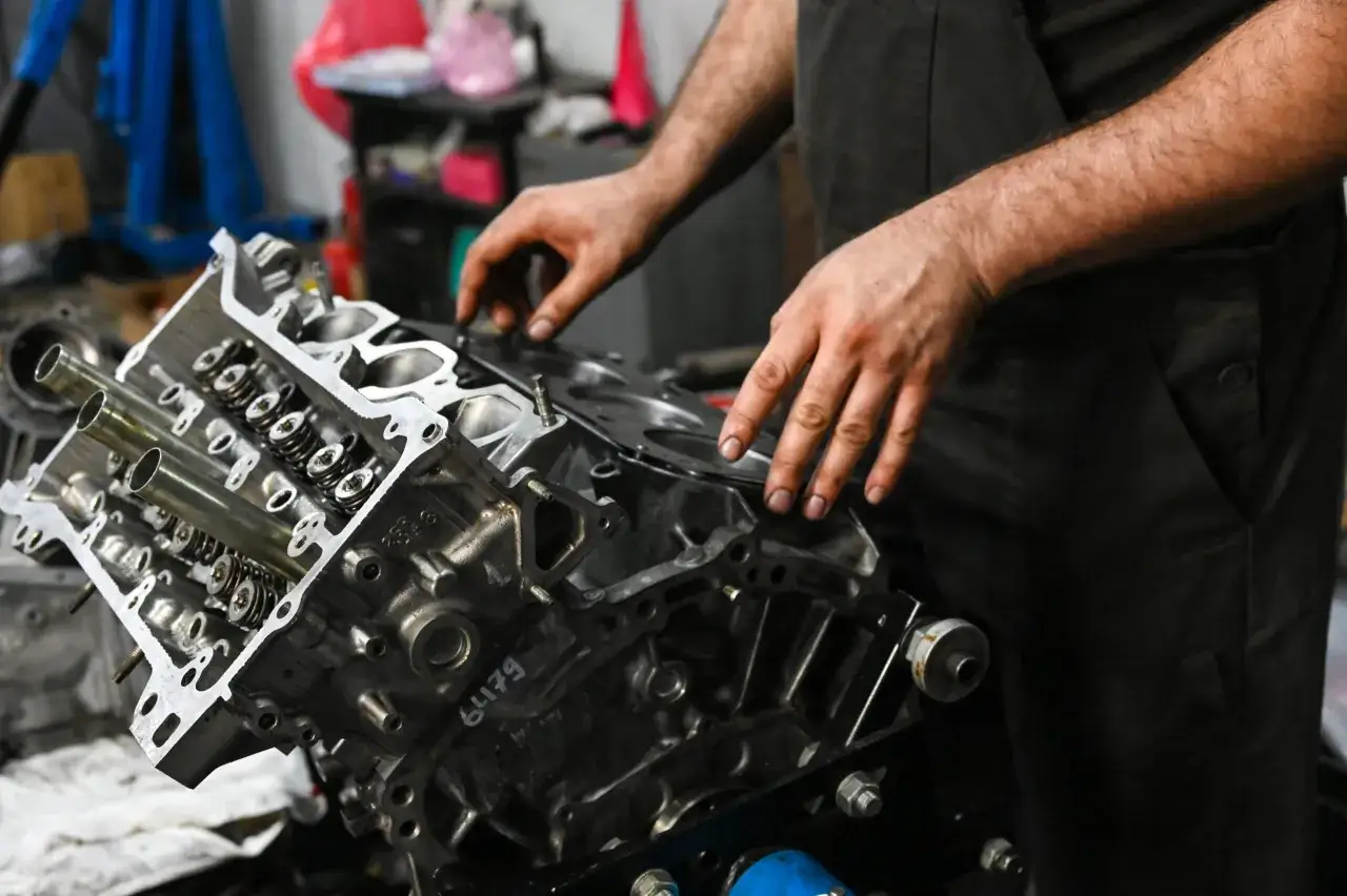Meccanico al lavoro su un motore. La manutenzione è fondamentale per sapere quanti km può fare un'auto.