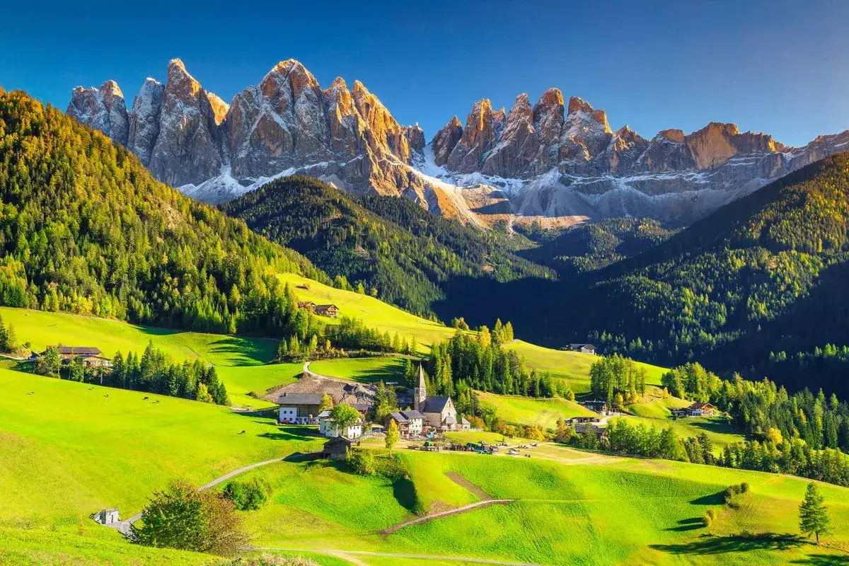Malownicze zielone wzg&oacute;rza i ośnieżone szczyty Dolomit&oacute;w. Idealne miejsce na **dolomity camping** i podziwianie natury.