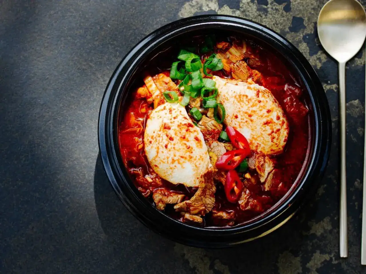 Hei&szlig;es, w&uuml;rziges Sundubu Jjigae mit zartem Tofu, Rindfleisch und Fr&uuml;hlingszwiebeln in einer roten Br&uuml;he.