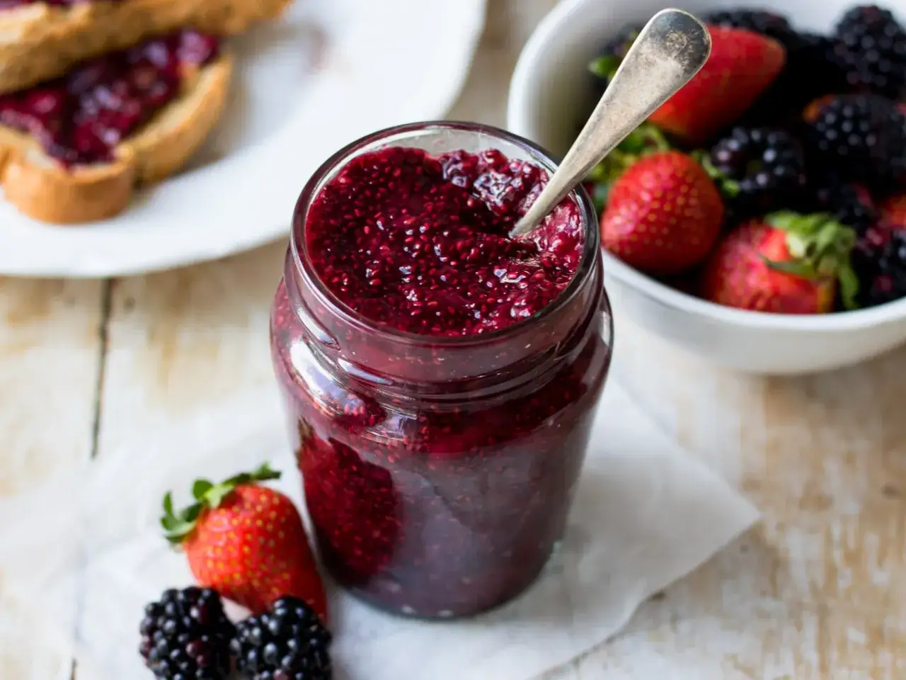 Frische Beeren-Chia-Marmelade, perfekt für die Schwangerschaft. Dazu Toast mit Marmelade und eine Schüssel voller Beeren.