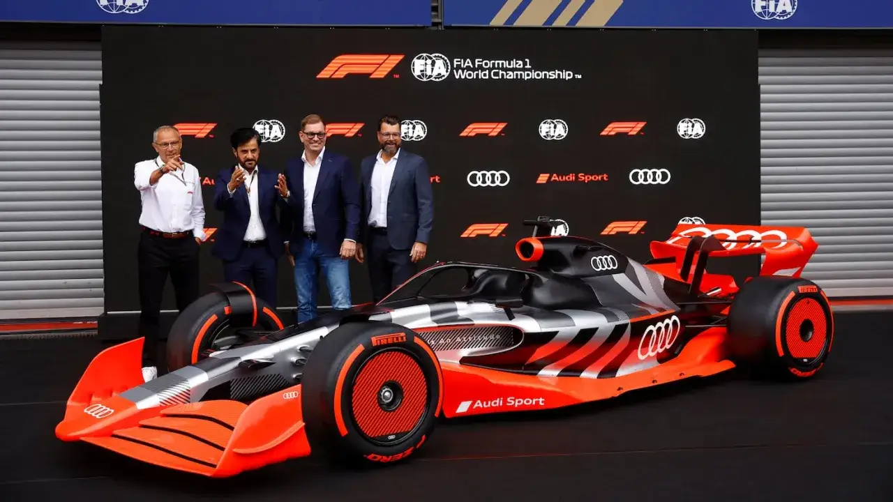 El nuevo coche de **Audi F1** se presenta con un diseño futurista en negro, plata y naranja vibrante.