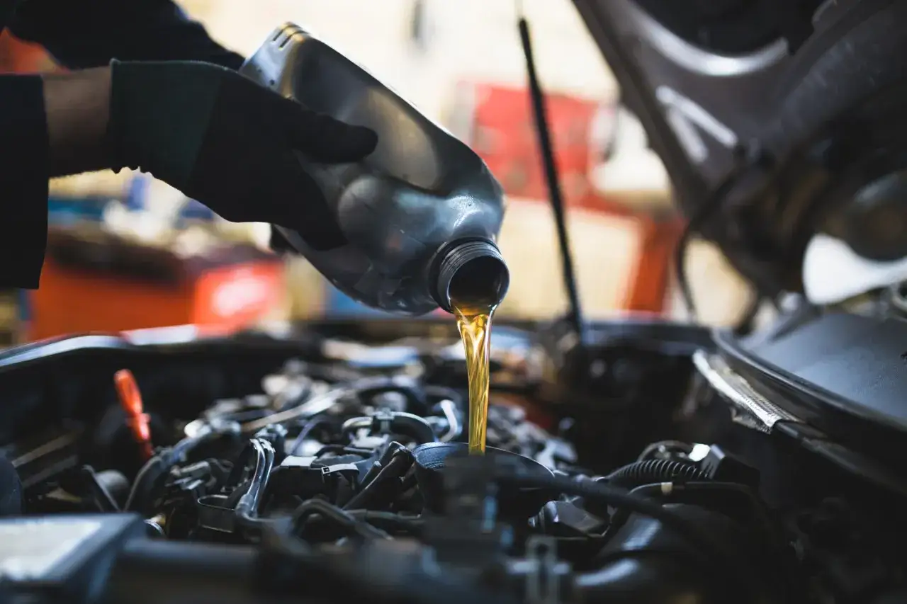Wymiana oleju i filtrów w dieslu – poznaj koszty. Mechanik nalewa świeży olej do silnika.