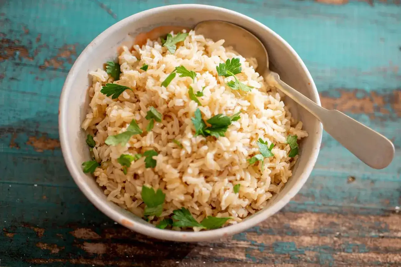 Un tazón de arroz integral recién cocido, adornado con perejil fresco, listo para ser disfrutado.