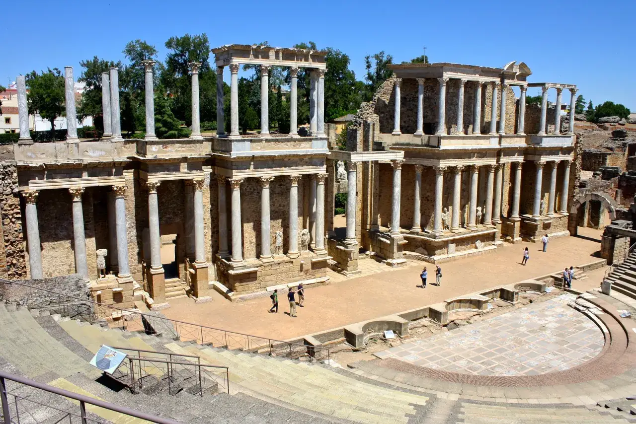 Majestic roman ruins in Spain, a theatre with grand columns and tiered seating, where visitors explore history.