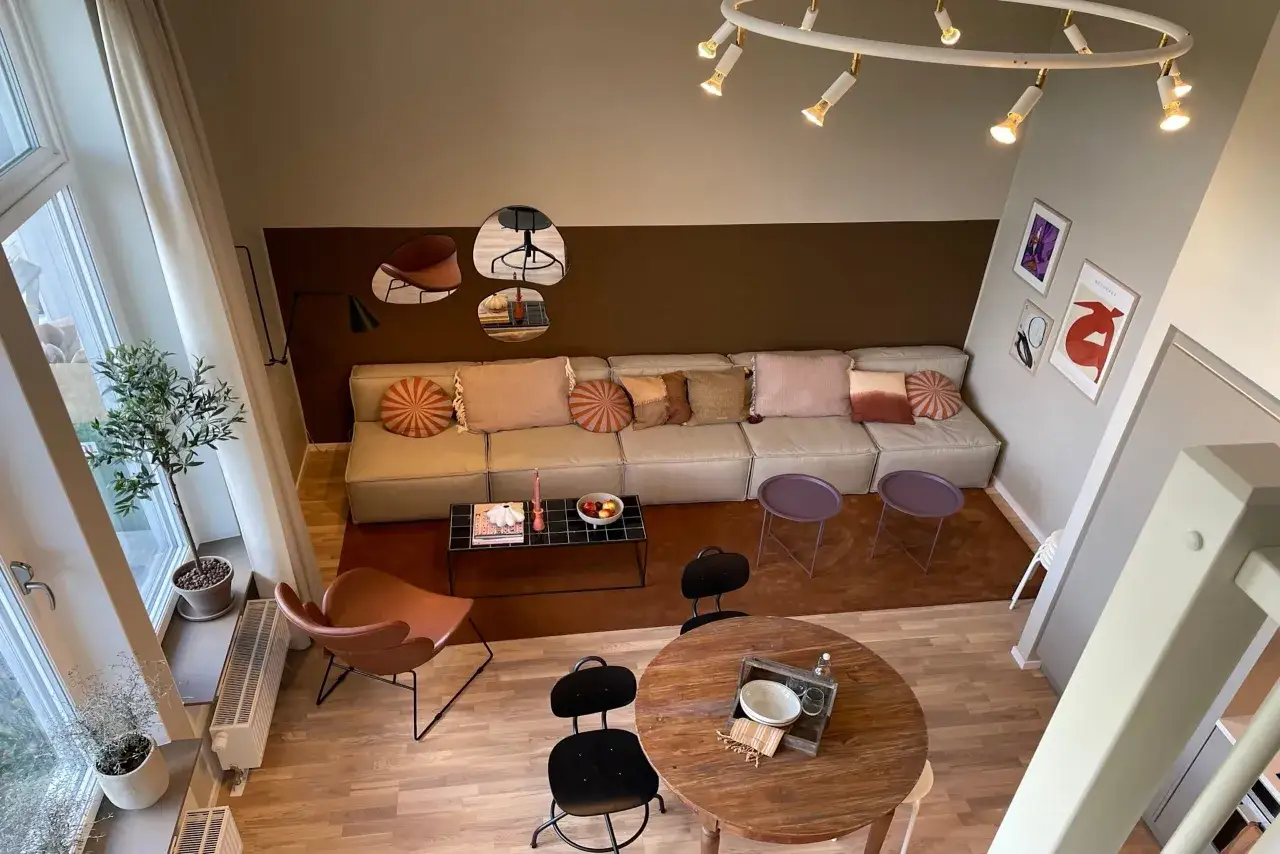 Ett hemma hos reportage visar en modern och mysig vardagsrumsmilj&ouml; med en stor soffa, runda bord och konst p&aring; v&auml;ggarna.