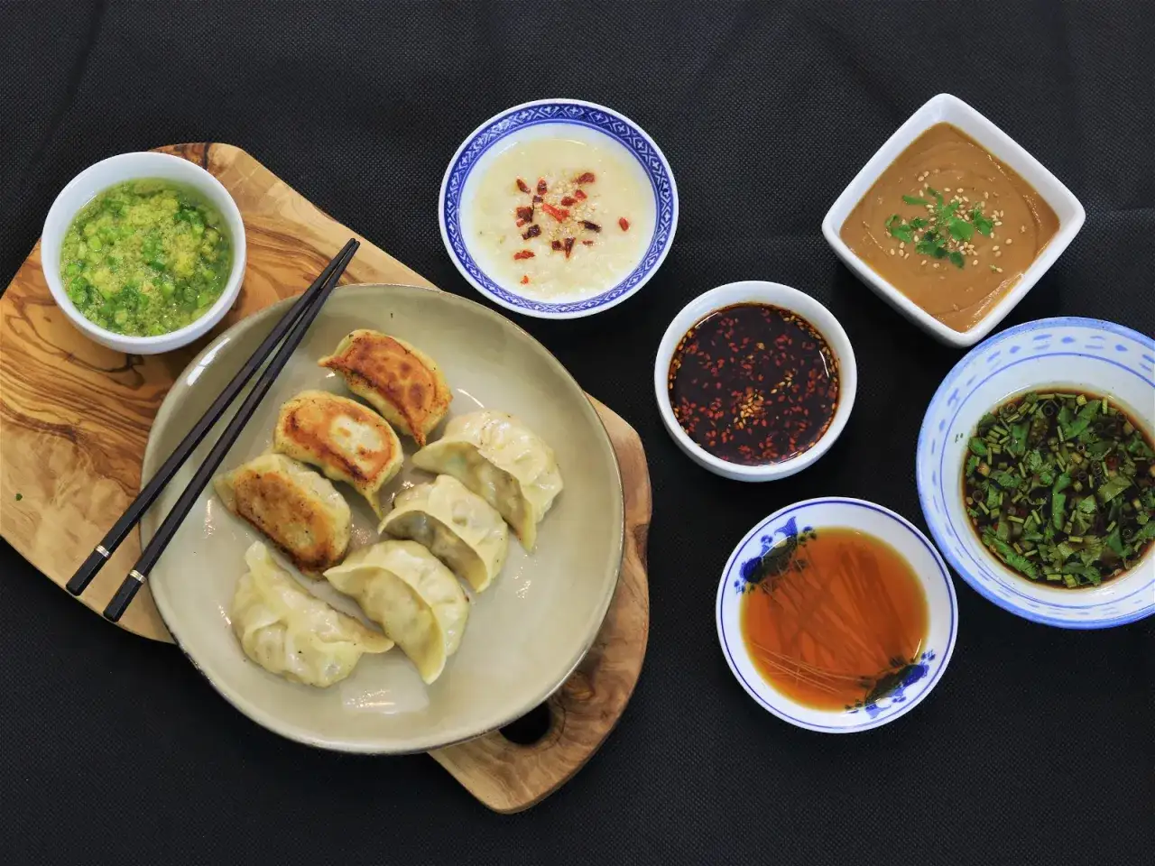 En tallrik med dumplings och flera sk&aring;lar med olika dumplings s&aring;s, redo att avnjutas.