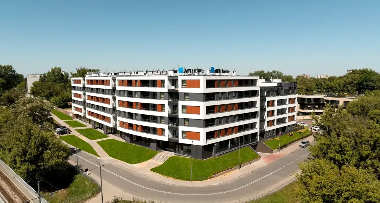 Nowoczesny blok mieszkalny AFI Home na Targówku Mieszkaniowym, otoczony zielenią.