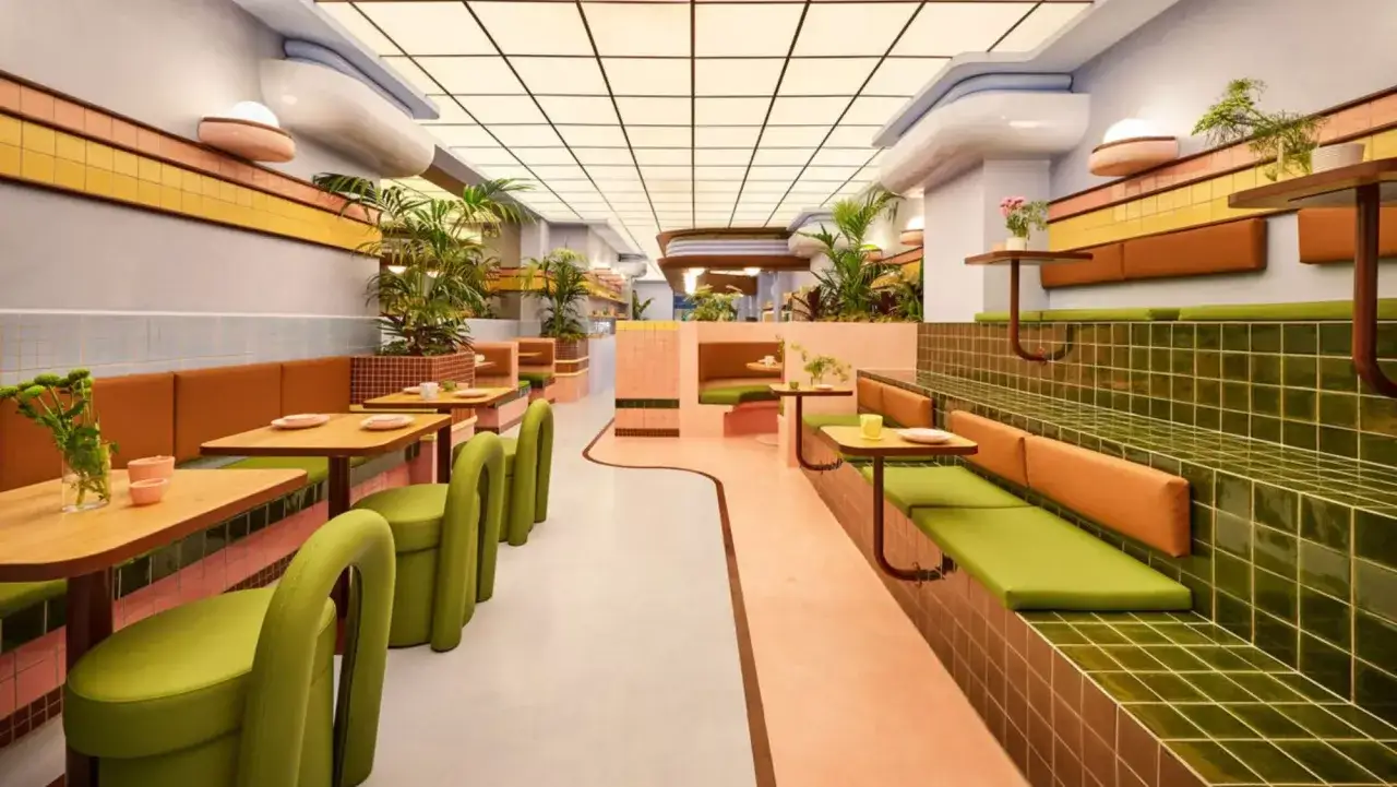 Un restaurante con diseño retro, donde la **restauración** se vive en cada detalle: asientos verdes, paredes rosas y plantas.