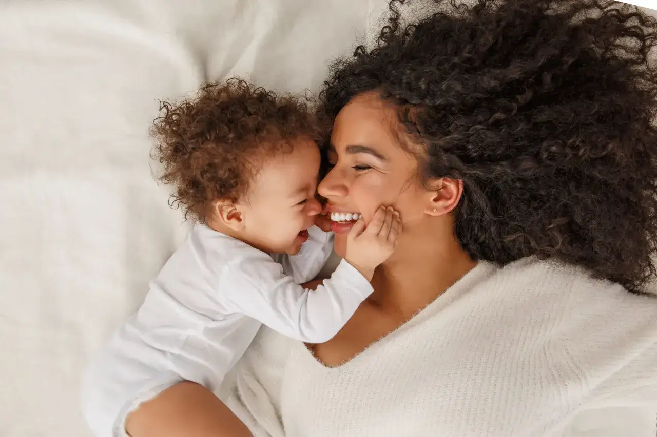 Ein Baby kuschelt sich an seine Mutter. Die liebevolle Nähe zeigt das Konzept des Attachment Parenting.