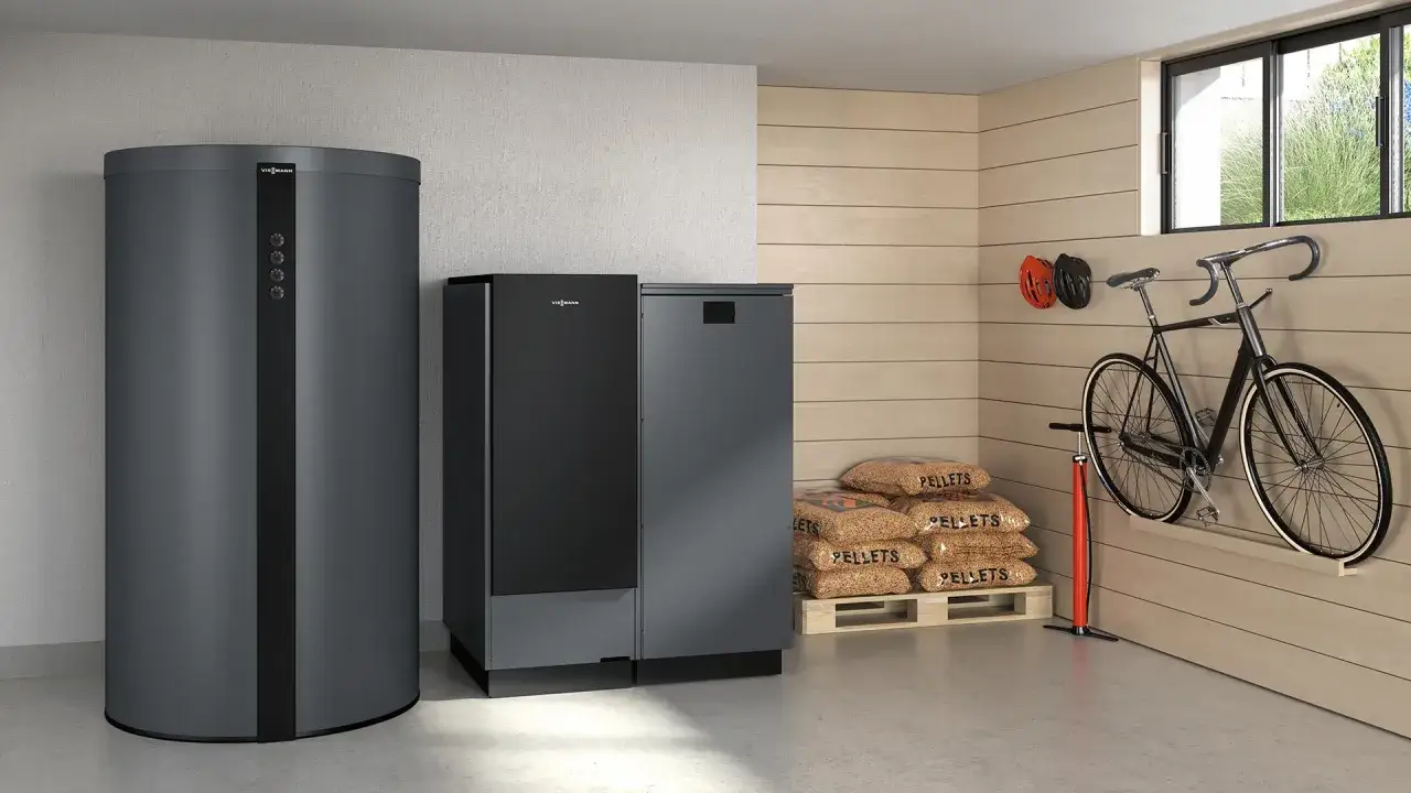 Système de chauffage à granulés Viessmann avec réservoir d'eau et unité de combustion, entouré de sacs de granulés, d'un vélo et de casques.