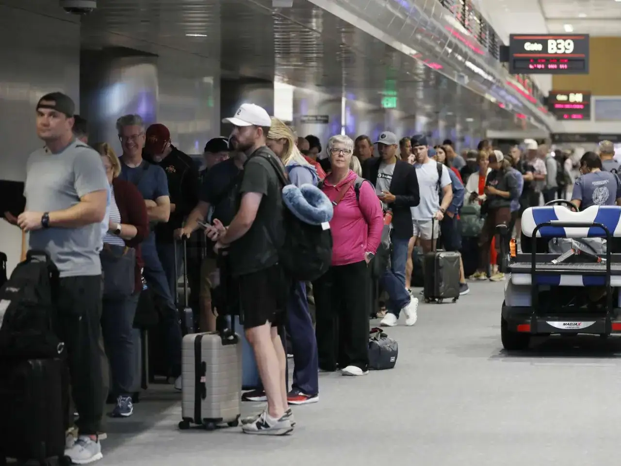 Kolejka do **boarding** na lotnisku. Ludzie z bagażami czekają na wejście do samolotu przy bramce B39.