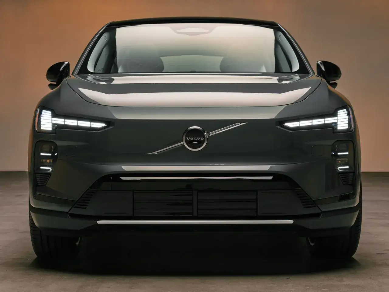 Der Volvo EX90, ein elegantes Elektro-SUV, pr&auml;sentiert sich frontal mit markanten LED-Scheinwerfern und dem ikonischen Volvo-Logo.