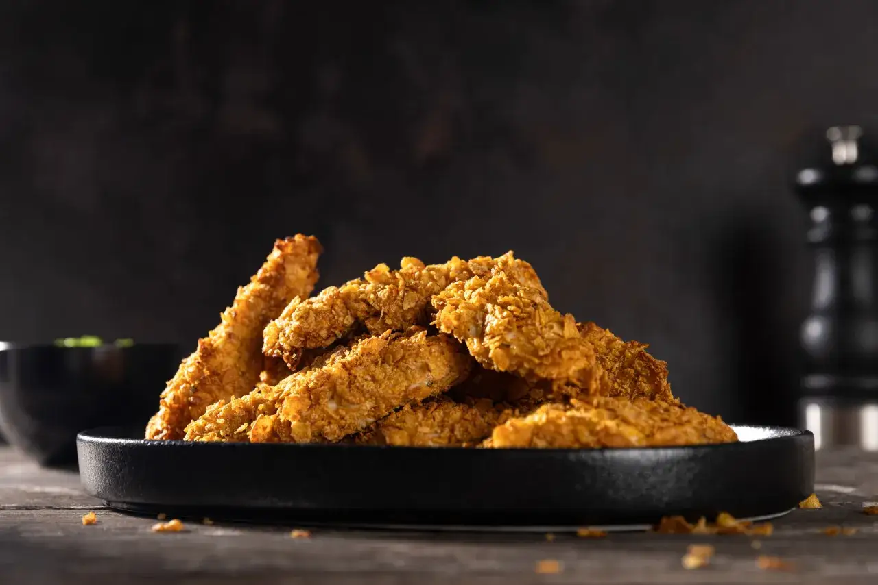Knusprige chicken nuggets auf einem schwarzen Teller, bereit zum Genießen.