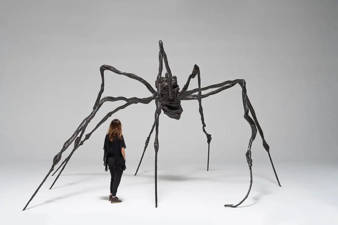 Une femme observe la sculpture monumentale d'une araignée,