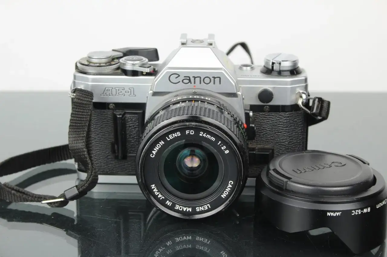 En klassisk Canon AE-1 med objektiv och motljusskydd. Perfekt f&ouml;r att f&aring;nga tidl&ouml;sa &ouml;gonblick.