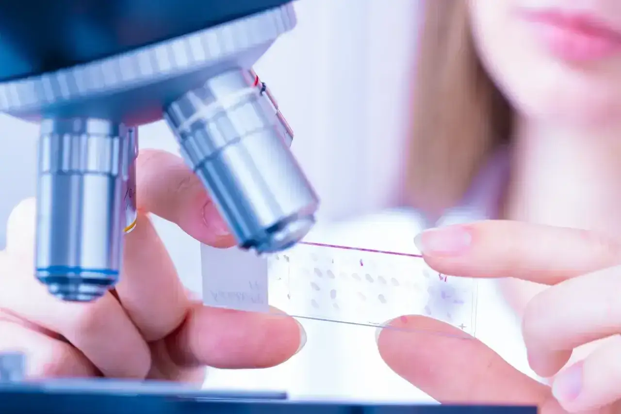 Badaczka przygotowuje preparat do badania pod mikroskopem, kluczowy etap w diagnostyce patomorfologia.