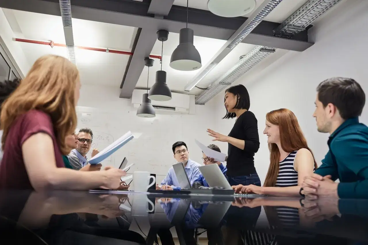 Gruppo di persone in un **assessment center** discute idee attorno a un tavolo.