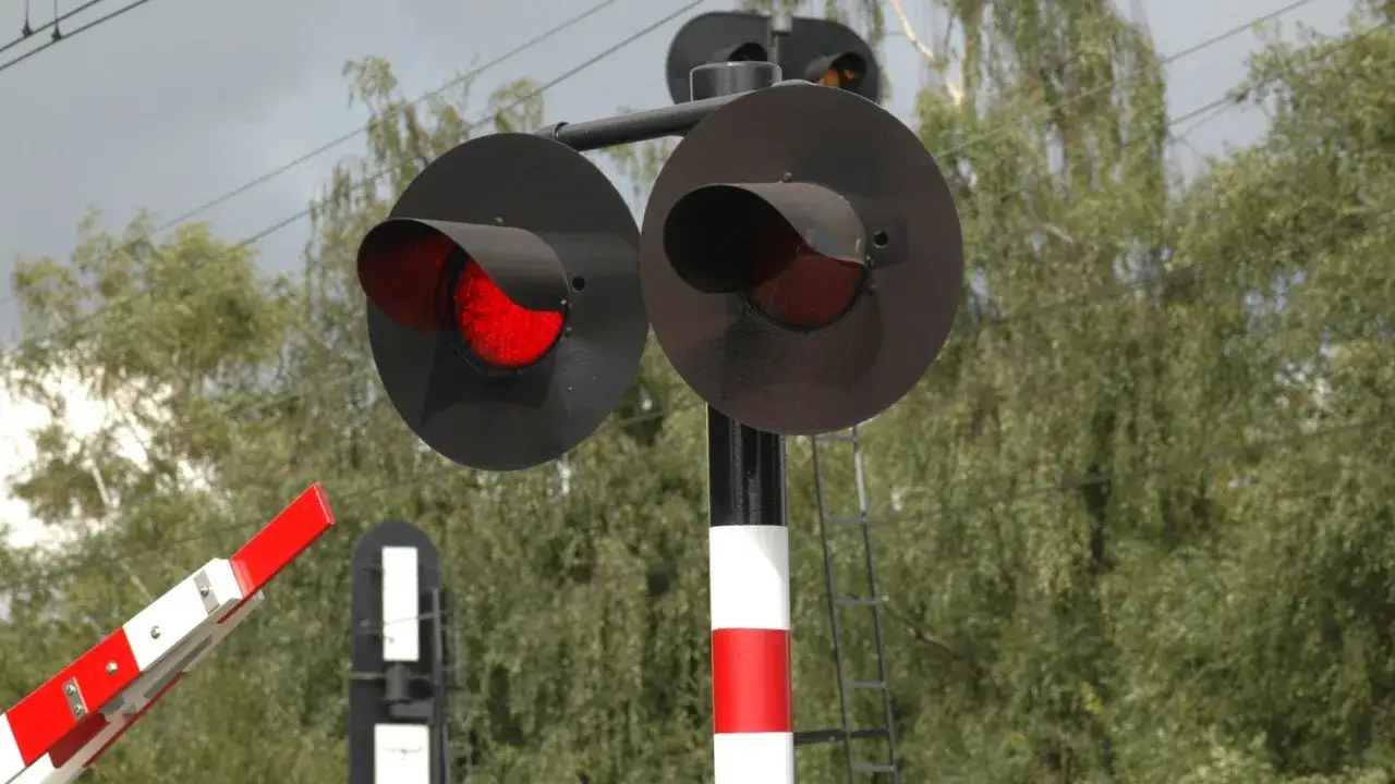 Sygnalizacja kolejowa z czerwonym światłem i opuszczonym rogatkiem. Zastanawiasz się, po jakim czasie przychodzi mandat z przejazdu kolejowego?