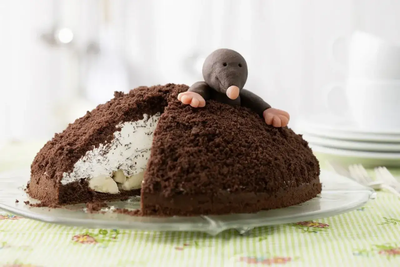 Ein Maulwurfkuchen-Rezept, das mit einer süßen Marzipan-Maus dekoriert ist. Der Kuchen ist mit Schokoladenstreuseln bedeckt und hat eine cremige Füllung.