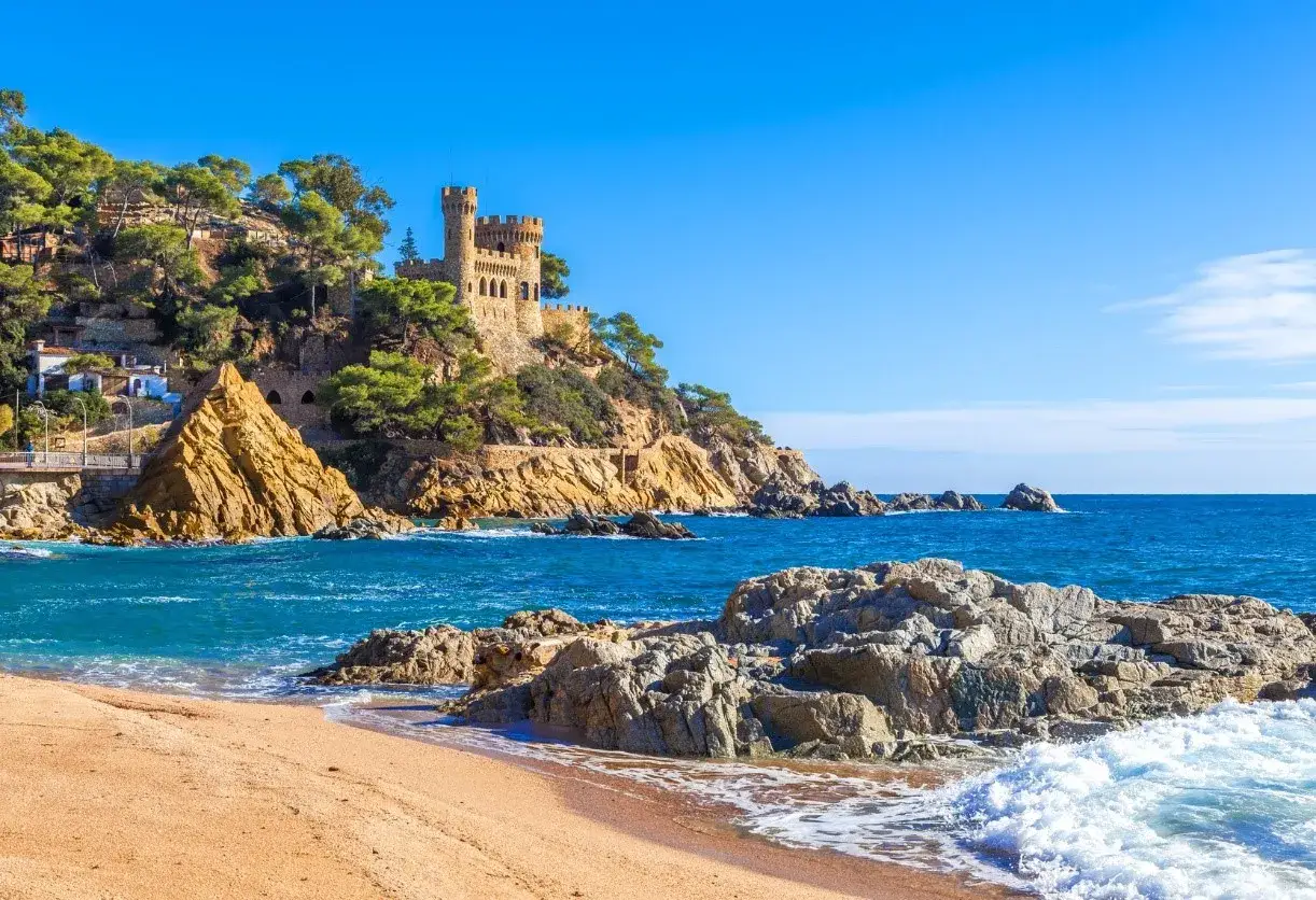Piękna plaża w Lloret de Mar, idealna na lipiec. Pogoda dopisuje, woda kusi błękitem, a zamek na wzgórzu dodaje uroku.