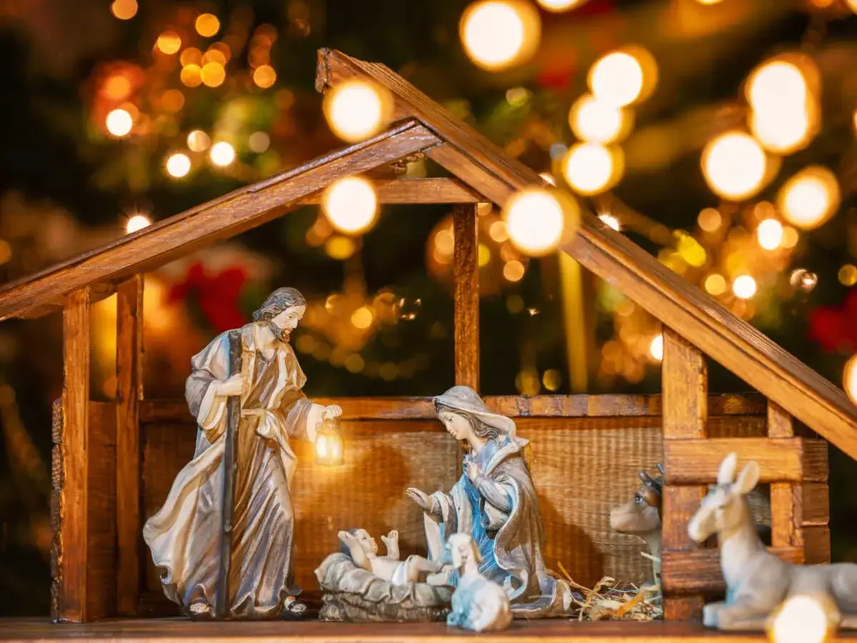 Une idée crèche de Noël originale : Joseph, Marie et l'enfant Jésus dans une étable illuminée par des guirlandes scintillantes.
