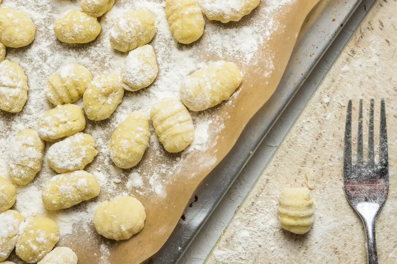 Gnocchis faits maison, prêts pour la cuisson. Une fourchette à côté suggère la prochaine étape de cette recette gnocchi.