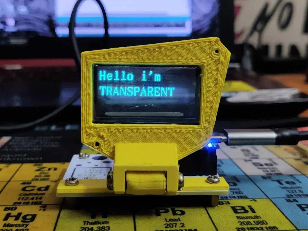 Ż&oacute;łta obudowa z wyświetlaczem transparent oled, na kt&oacute;rym widnieje napis 