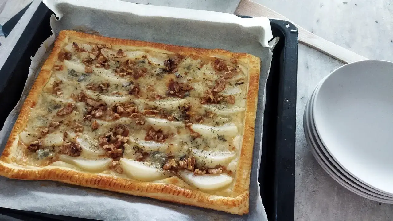 Sernik z gorgonzolą i gruszką na cieście francuskim, posypany orzechami i ziołami.
