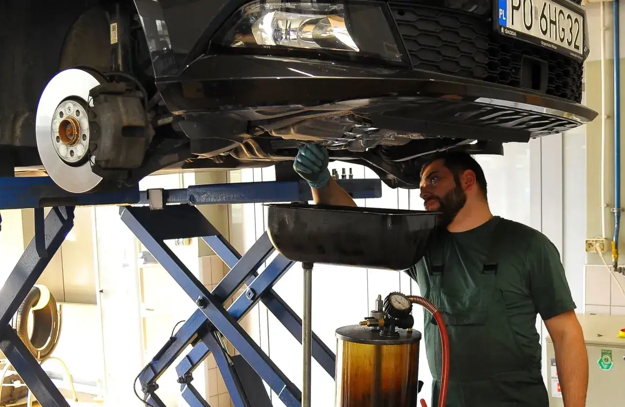 Mechanik wymienia przepracowany olej silnikowy w samochodzie podniesionym na podnośniku.