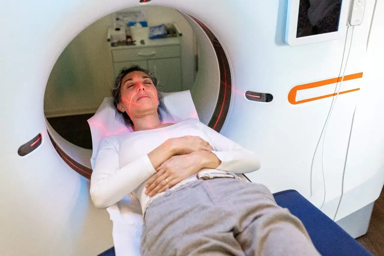 Kobieta leży w skanerze MRI, przygotowując się do badania. Czerwone linie na jej twarzy wskazują, jak przetrwać rezonans magnetyczny, zachowując spok&oacute;j.