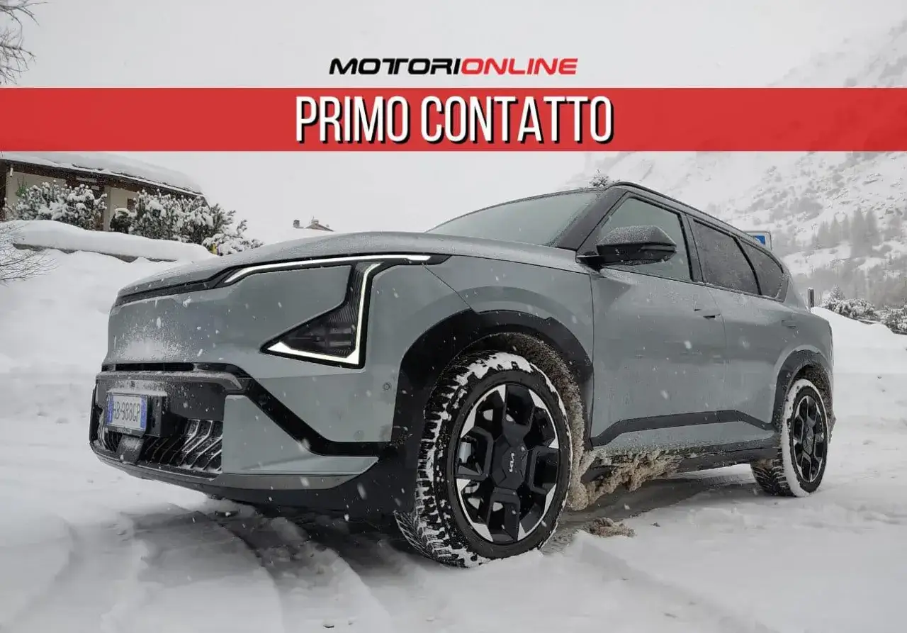 Un'auto elettrica 4x4 grigia affronta la neve in montagna, pronta per ogni avventura invernale.